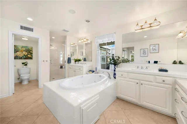 a large white bathroom with a double vanity sink a mirror and a bathtub