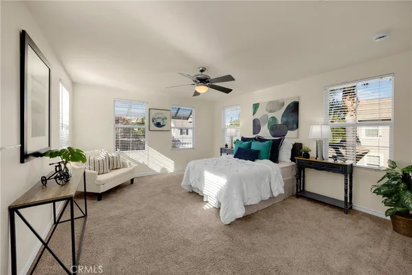 a spacious bedroom with a bed couch and windows