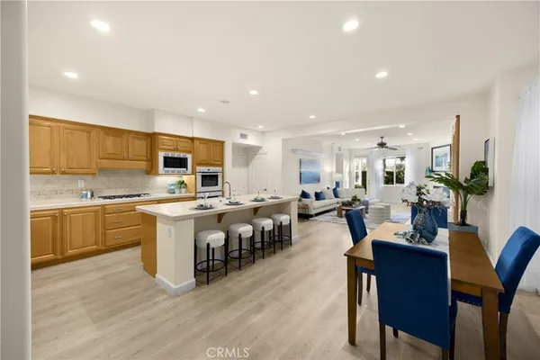 a living room with stainless steel appliances furniture a dining table and kitchen view