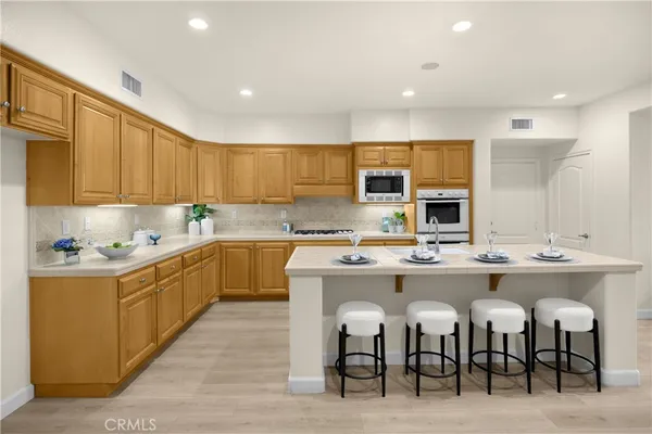 a kitchen with cabinets a sink dishwasher a stove and chairs with wooden floor
