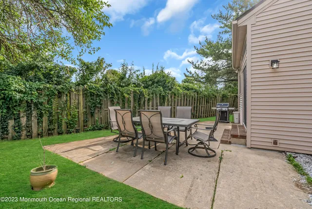 a view of a patio with table and chairs potted plants and large tree