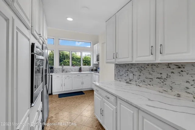 a kitchen with white cabinets and window