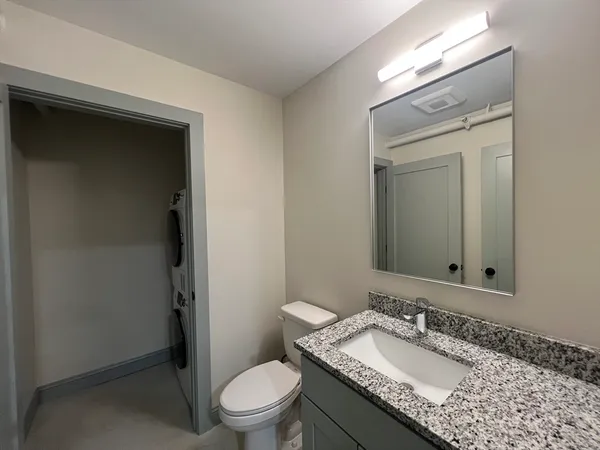 a bathroom with a granite countertop sink toilet a mirror and shower