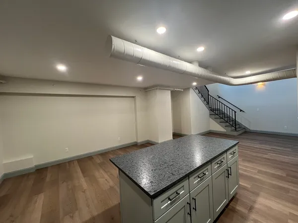 a kitchen with stainless steel appliances granite countertop a sink a stove and a wooden floor
