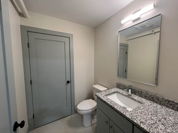 a bathroom with a granite countertop sink toilet and shower