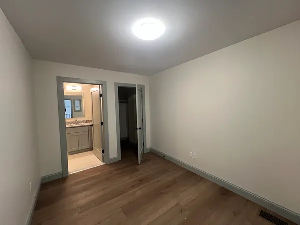 a view of a hallway with wooden floor and a kitchen