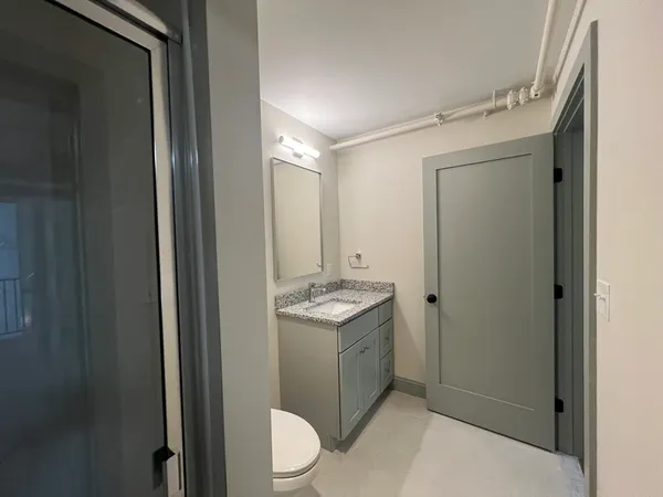 a bathroom with a granite countertop sink a mirror and a toilet