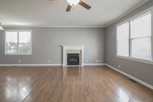 a view of an empty room with a window and wooden floor