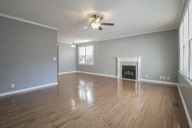 an empty room with wooden floor and ceiling fan