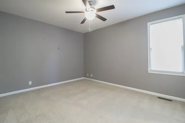an empty room with a window and a fan