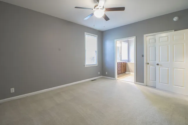 an empty room with chandelier fan and windows