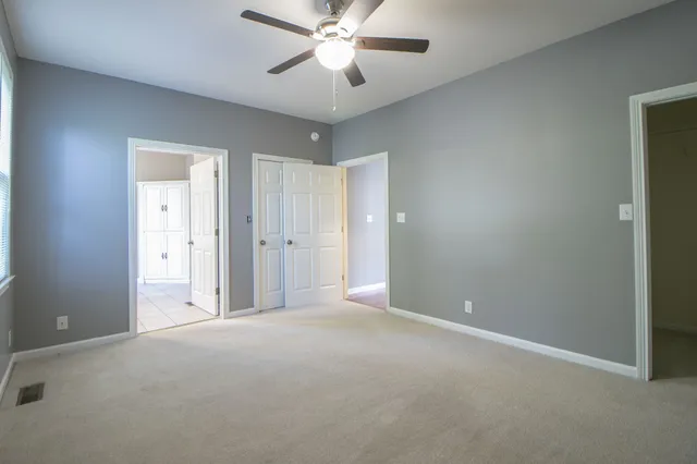 an empty room with closet and a ceiling fan