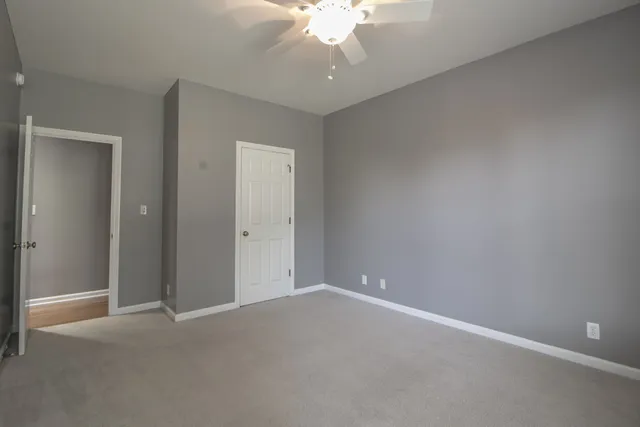 an empty room with a chandelier fan and closet area