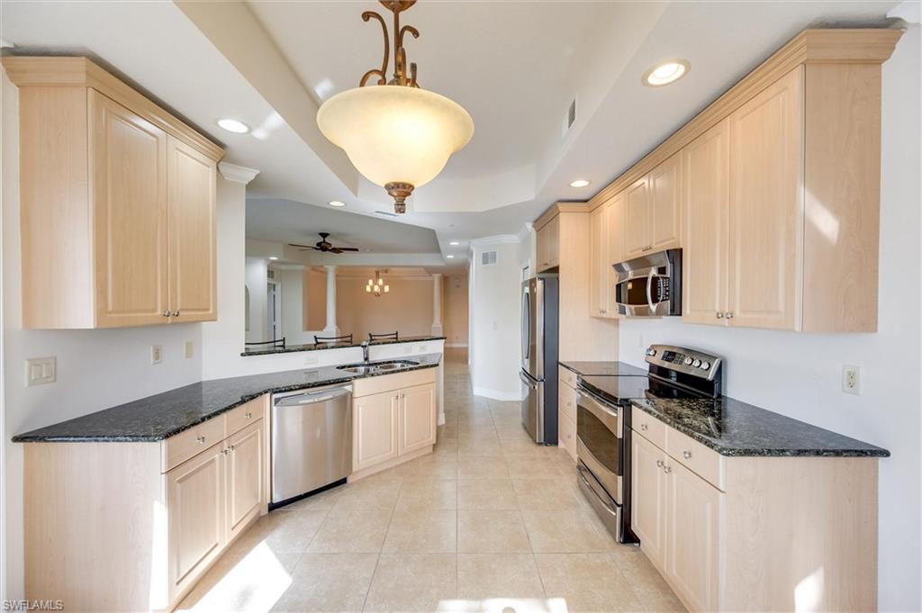3600 Lansing Loop, Unit 103 Estero, FL 33928 - Photo 16 of 33 a large kitchen with granite countertop a sink and dishwasher a stove top oven with wooden floor