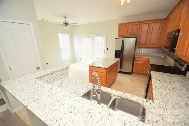 a kitchen with stainless steel appliances kitchen island granite countertop a sink refrigerator and cabinets