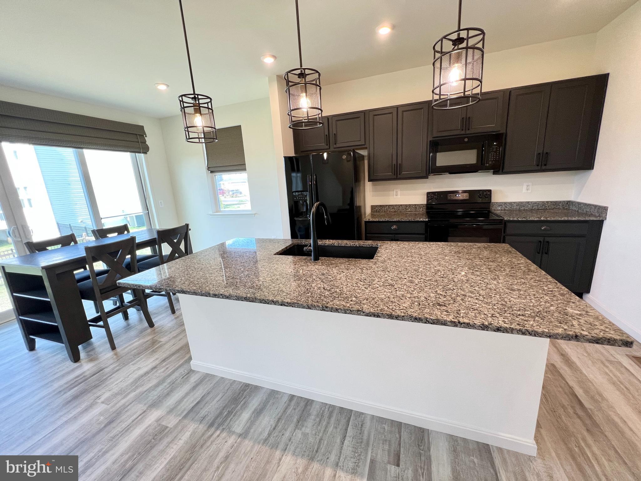 6366 Pointer Lane King George, VA 22485 - Photo 11 of 48 a kitchen with stainless steel appliances granite countertop a refrigerator a sink dishwasher a stove and a dining table with wooden floor