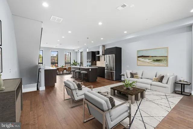 a living room with stainless steel appliances kitchen island granite countertop furniture and a wooden floor