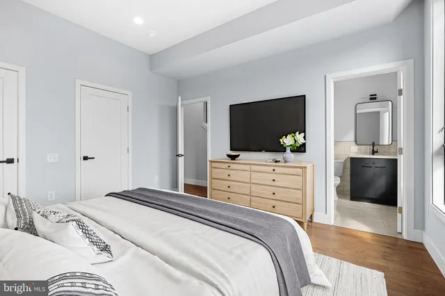 a bedroom with a bed and a flat screen tv in white dresser