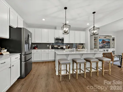 a kitchen with stainless steel appliances kitchen island granite countertop a table chairs and a refrigerator
