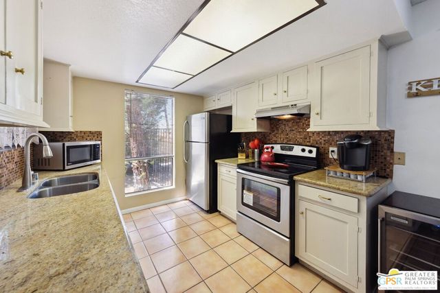 a kitchen with stainless steel appliances granite countertop a dining table chairs stove and refrigerator