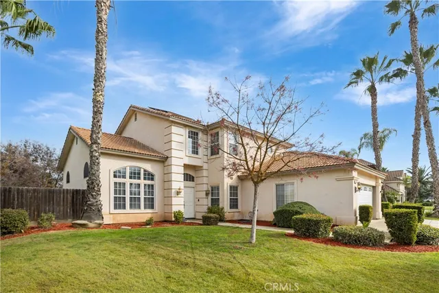 a view of a white house next to a yard with potted plants and wooden fence