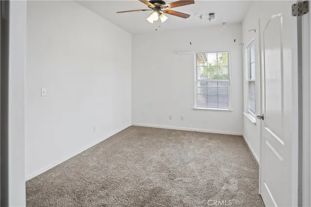 an empty room with chandelier fan and windows