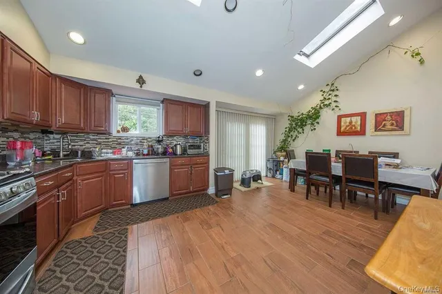 a kitchen with stainless steel appliances granite countertop wooden cabinets a dining table and chairs