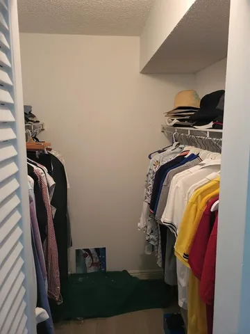 a view of walk in closet with clothes and shoes