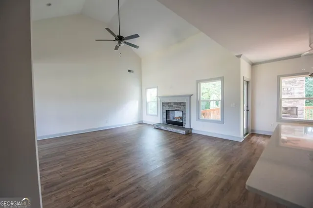 an empty room with wooden floor fireplace and windows