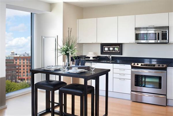 2 Earhart Street, Unit 204 Cambridge, MA 02141 - Photo 2 of 11 a kitchen with a table chairs microwave and cabinets