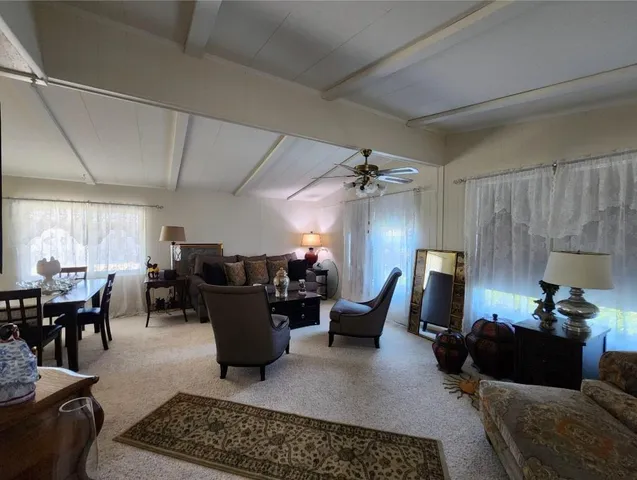 a living room with furniture kitchen view and a large window