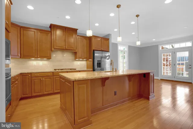 a large kitchen with stainless steel appliances granite countertop a sink a stove and a wooden floors