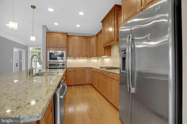a large kitchen with stainless steel appliances kitchen island granite countertop a refrigerator and a sink