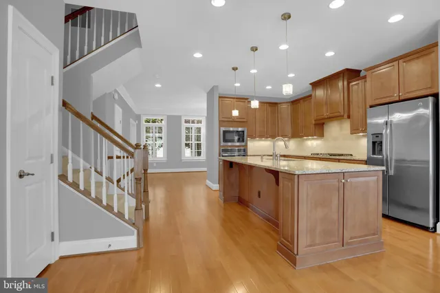 a kitchen with stainless steel appliances kitchen island granite countertop a refrigerator and a stove top oven