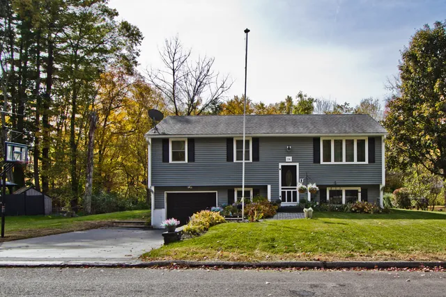 a front view of a house with a garden and tree