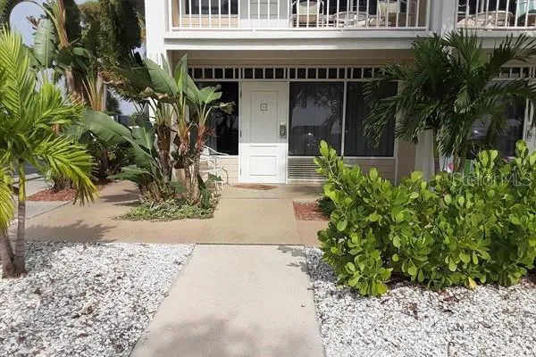 a view of yellow house with a large windows and plants