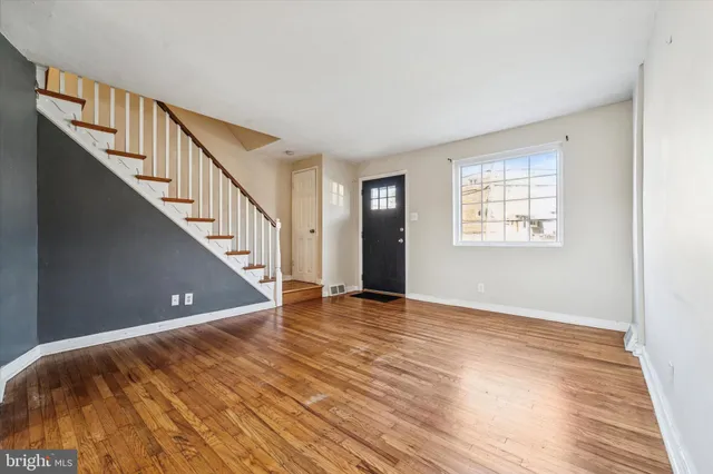 a view of an empty room with wooden floor and stairs