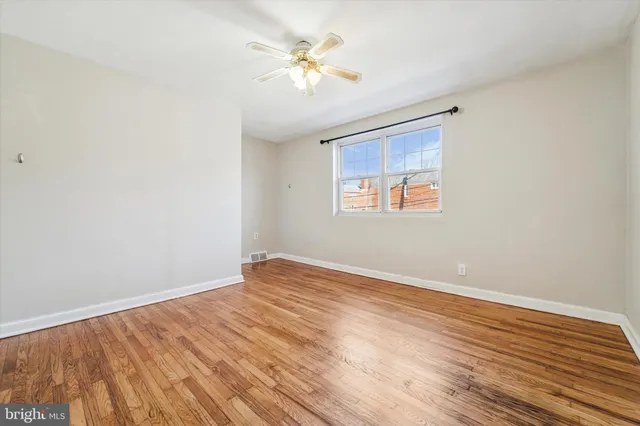 a view of an empty room with window and wooden floor