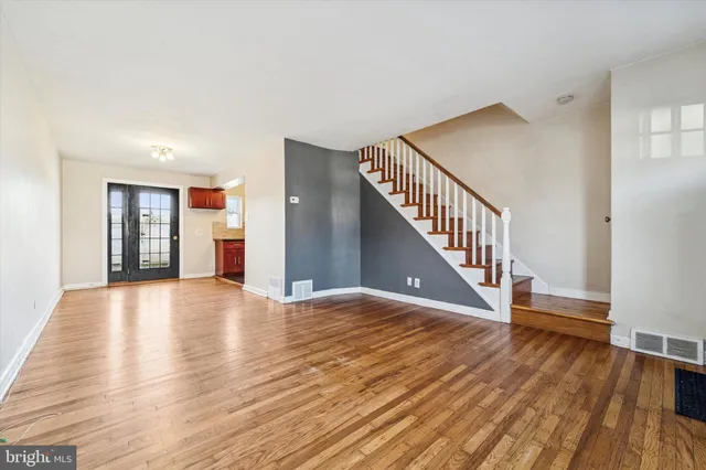 a view of empty room with wooden floor and fan