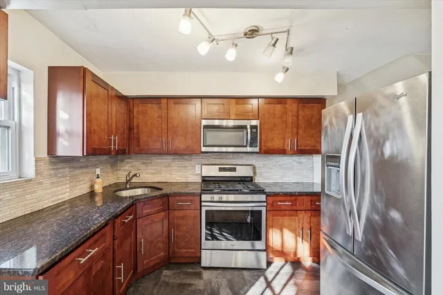 a kitchen with granite countertop a refrigerator stove and sink