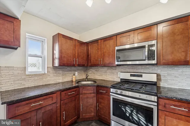 a kitchen with stainless steel appliances granite countertop a stove microwave and sink