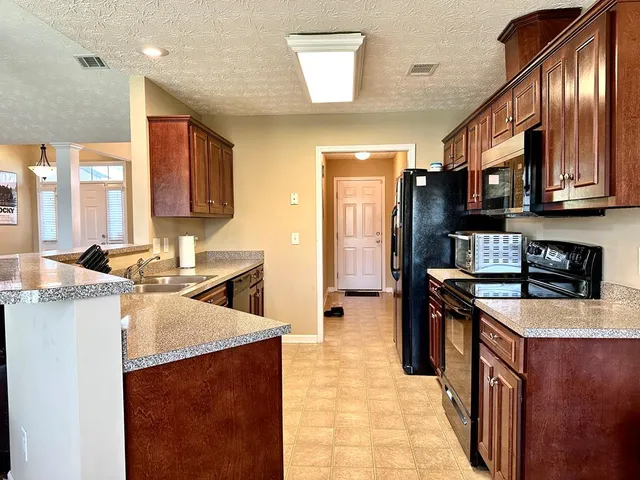 a kitchen with stainless steel appliances granite countertop a stove a sink dishwasher and a refrigerator
