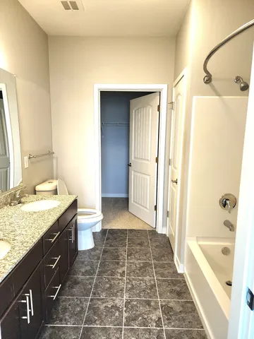 a bathroom with a granite countertop sink a toilet and shower