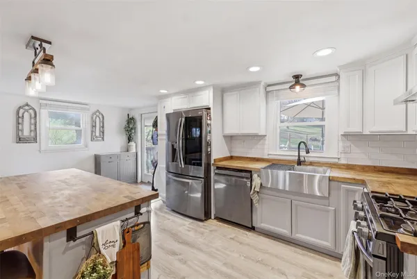 a kitchen with granite countertop a stove top oven a sink dishwasher and a refrigerator with wooden floor