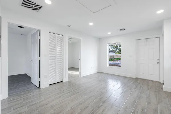 an empty room with wooden floor and windows
