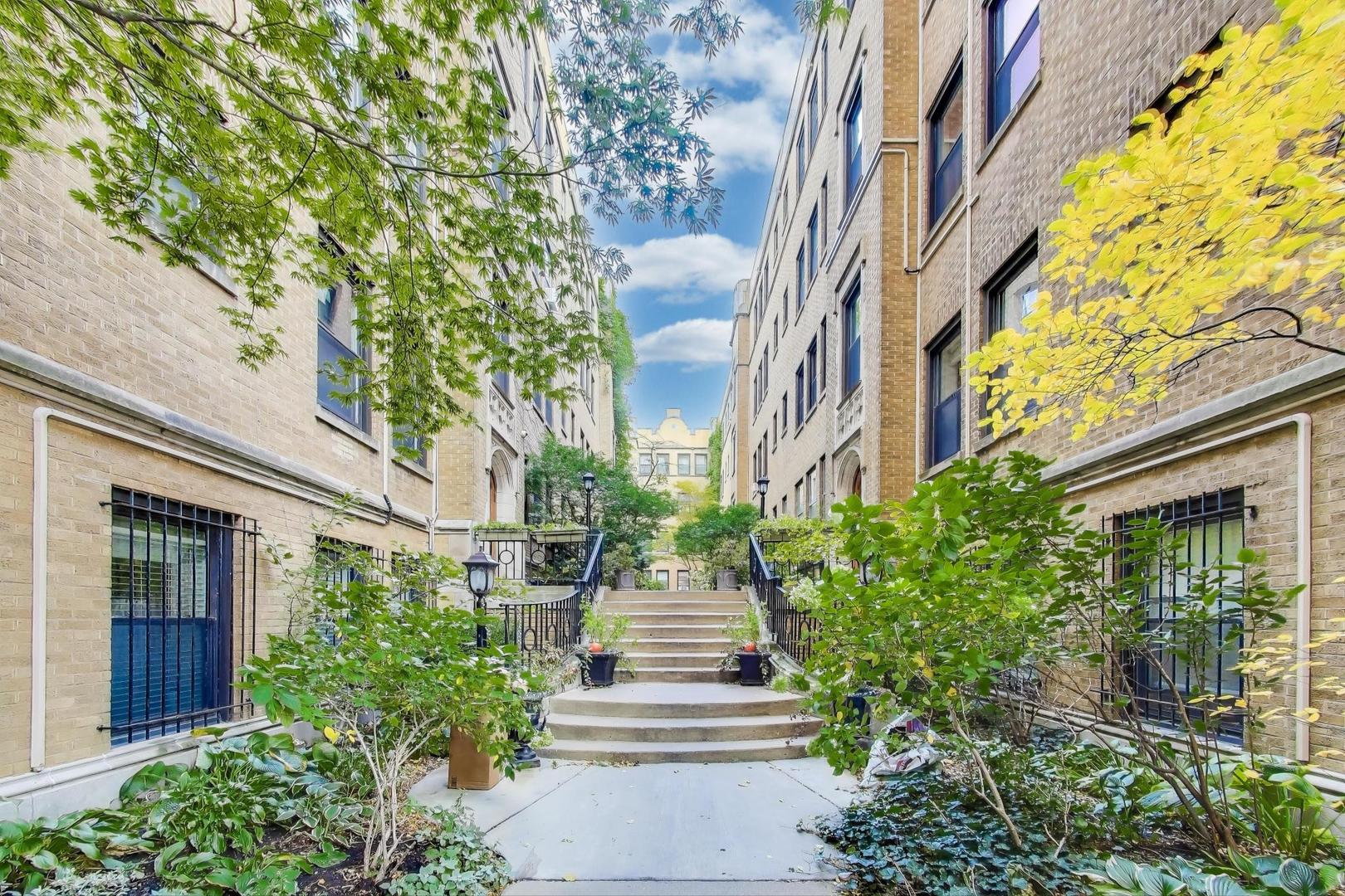 636 West Waveland Avenue, Unit 2E Chicago, IL 60613 - Photo 4 of 23 a view of a pathway of a house with plants and large trees