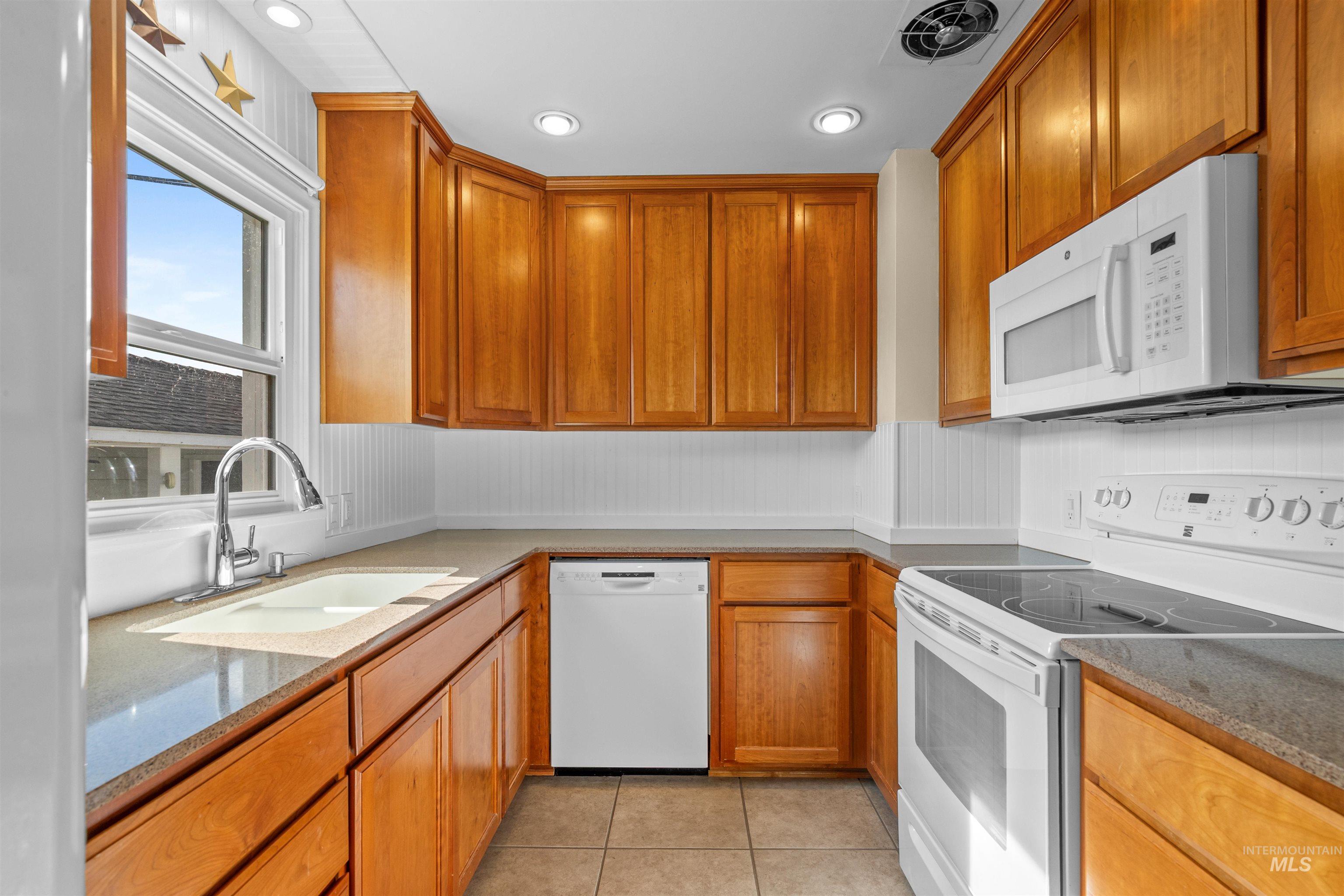 1303 4th Street Clarkston, WA 99403 - Photo 5 of 32 Kitchen with white appliances, light tile patterned flooring, stone counters, brown cabinetry, and recessed lighting