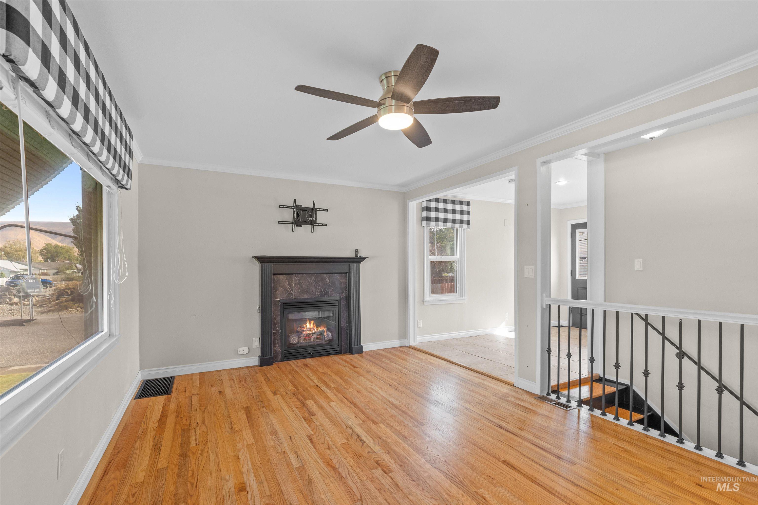 1303 4th Street Clarkston, WA 99403 - Photo 6 of 32 Unfurnished living room with wood finished floors, ornamental molding, a fireplace, and ceiling fan