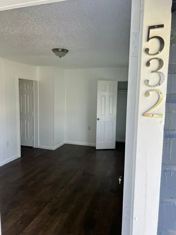 an empty room with wooden floor closet and windows
