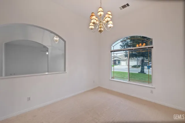 an empty room with wooden floor a ceiling fan a fireplace and windows